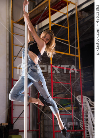 Young woman in ripped jeans performing pole dance 48612862