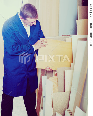 portrait of man in uniform choosing compressed densified wood in picture framing atelier 48613446
