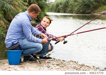 father and son fishing together on lake . 48613770