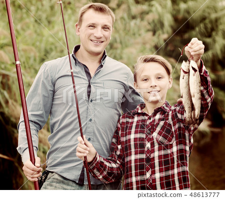 Glad father with son looking at fish on hook Glad father with son looking at fish on hook 48613777