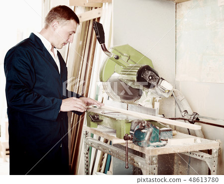 concentrated workman cutting wooden planks using circular saw 48613780
