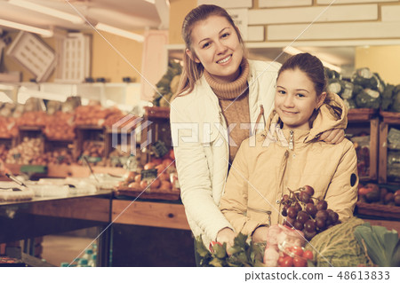 Smiling woman and girl looking for fresh delicious fruits Smiling woman and girl looking for fresh delicious fruits 48613833
