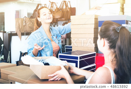 smiling teenager girl taking box with pairs from seller in shoes smiling teenager girl taking box with pairs from seller in shoes 48613892