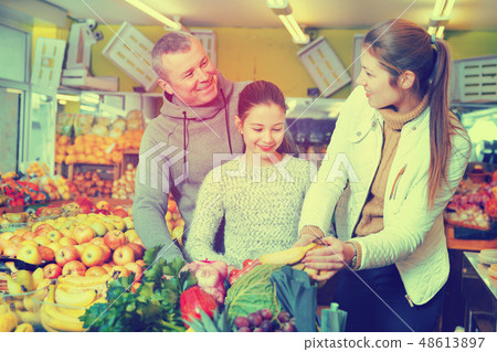 Parents with daughter choosing sweet bananas in fruit market Parents with daughter choosing sweet bananas in fruit market 48613897