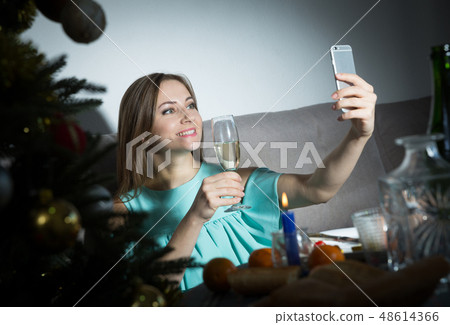 Woman taking selfie while celebrating Christmas Woman taking selfie while celebrating Christmas 48614366