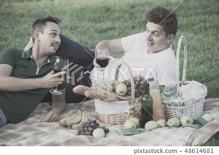 Two males friends gaily spending time together on picnic drinking wine Two males friends gaily spending time together on picnic drinking wine 48614681