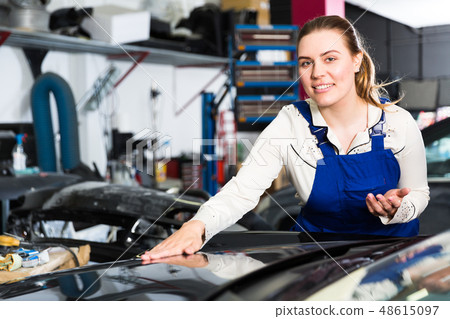 Woman mechanic demonstrating repainted car Woman mechanic demonstrating repainted car 48615097