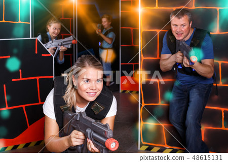 smiling girl with laser pistol playing laser tag with friends smiling girl with laser pistol playing laser tag with friends 48615131