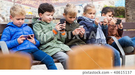 Five kidsare chatting on their smartphone Five kidsare chatting on their smartphone 48615137