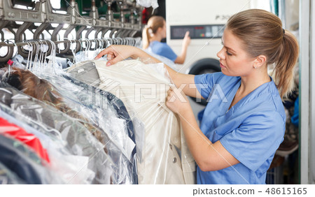 worker of laundry inspecting clothes after dry cleaning 48615165