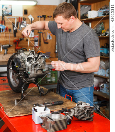 Man is repairing modern moto and looking on detail for it Man is repairing modern moto and looking on detail for it 48615311