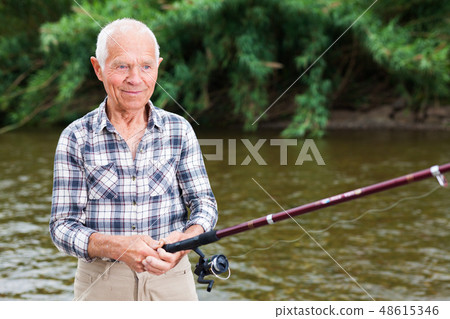 Mature man angling at riverside Mature man angling at riverside 48615346