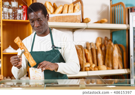 Baker packing pastry in paper bag 48615397