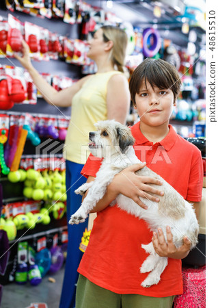 Portrait of happy teen boy with his little dog visiting pet supplies shop with mother 48615510