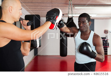 Trainer assisting african american in boxing Trainer assisting african american in boxing 48615516