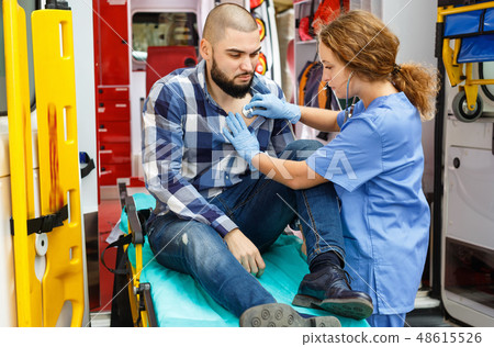 Emergency doctors providing first aid to man in ambulance auto Emergency doctors providing first aid to man in ambulance auto 48615526