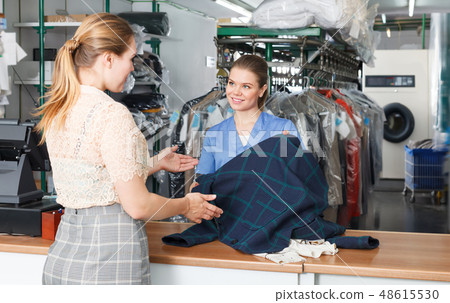 Smiling woman working with client in laundry 48615530