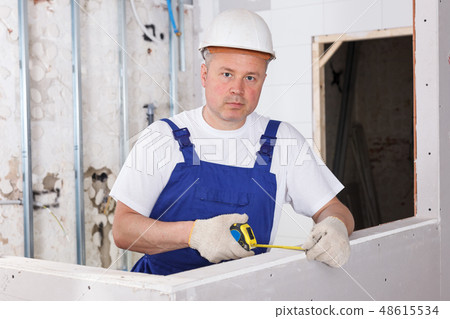 Builder measuring drywall construction Builder measuring drywall construction 48615534