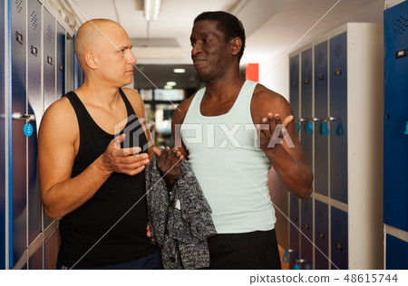 Two athletes chatting in the gym dressing room Two athletes chatting in the gym dressing room 48615744