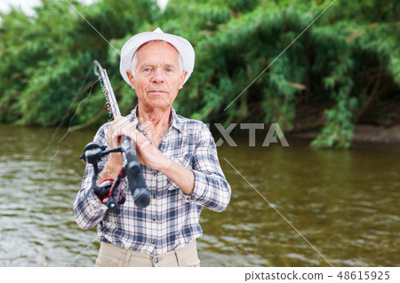 Mature fisherman with rod at riverside Mature fisherman with rod at riverside 48615925