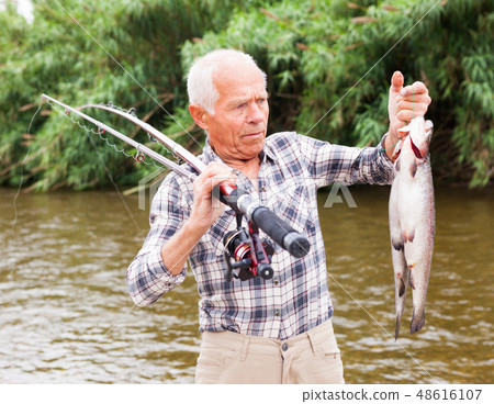 Mature fisherman examining catch Mature fisherman examining catch 48616107