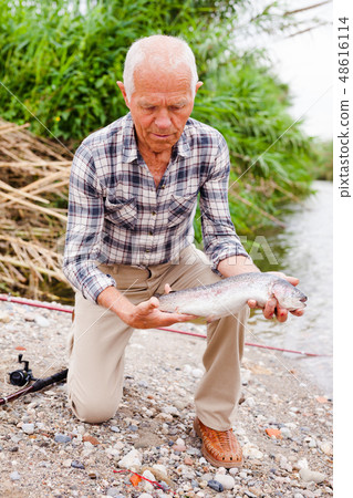 Mature fisherman examining catch 48616114