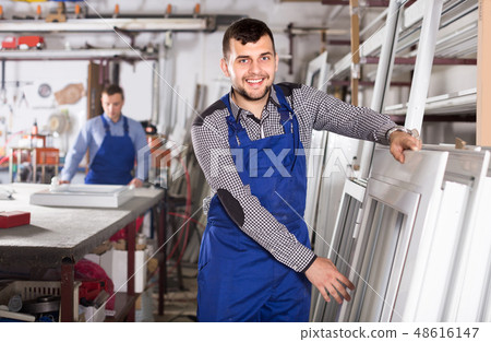 Young laborer is inspecting the window frame Young laborer is inspecting the window frame 48616147
