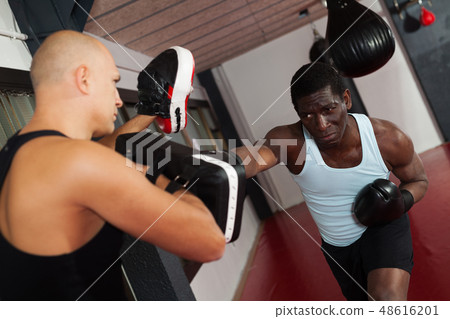 Men practicing effective techniques of self-defence during individual class in training room Men practicing effective techniques of self-defence during individual class in training room 48616201
