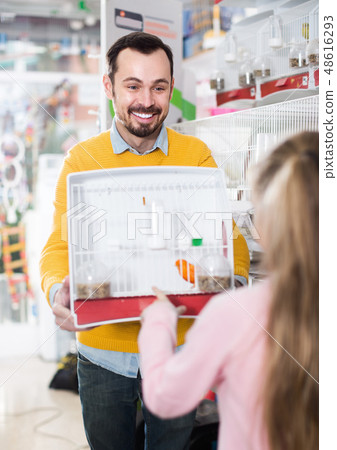 Smiling male seller offering cage with canary bird 48616293