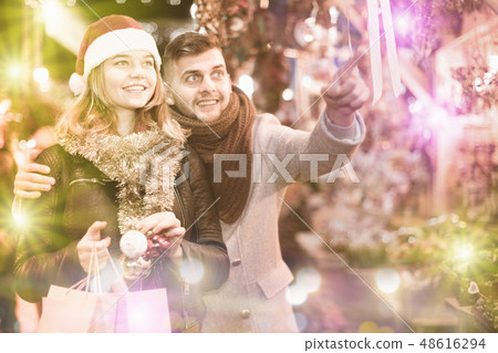 Couple in hat at Christmas Fair, man points to decorations Couple in hat at Christmas Fair, man points to decorations 48616294