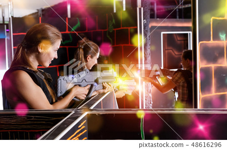 Guys and girls in vests and with laser pistols playing lasertag Guys and girls in vests and with laser pistols playing lasertag 48616296