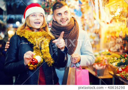 Positive young couple at Christmas fair, girl points to toys Positive young couple at Christmas fair, girl points to toys 48616298