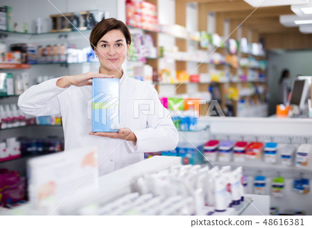 Smiling female pharmacist offering products Smiling female pharmacist offering products 48616381