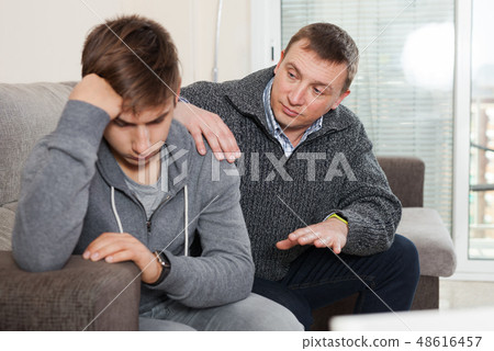 Father soothes teenager son after quarrel Father soothes teenager son after quarrel 48616457