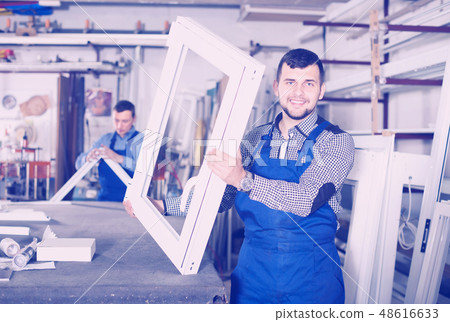 smiling male professional labours with finished PVC profiles and windows 48616633