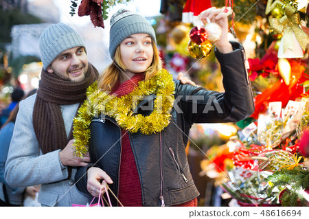 Girl with boy choosing decorations at Christmas market Girl with boy choosing decorations at Christmas market 48616694