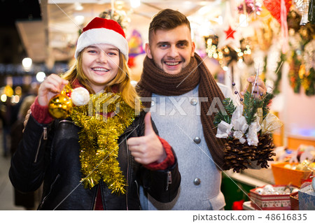 Joyful young couple in Christmas hat delighted with purchases Joyful young couple in Christmas hat delighted with purchases 48616835