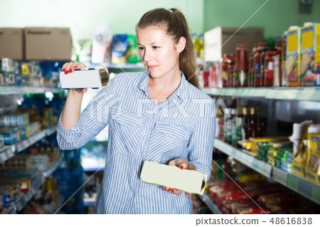 Woman in the shop holding preserved of tuna Woman in the shop holding preserved of tuna 48616838