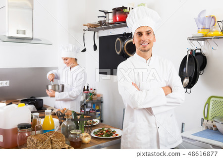 Smiling man chef cooking food at kitchen Smiling man chef cooking food at kitchen 48616877