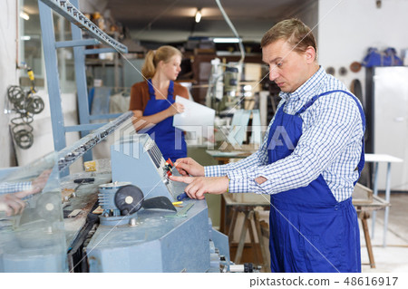 Craftsman working on glass beveling machine Craftsman working on glass beveling machine 48616917
