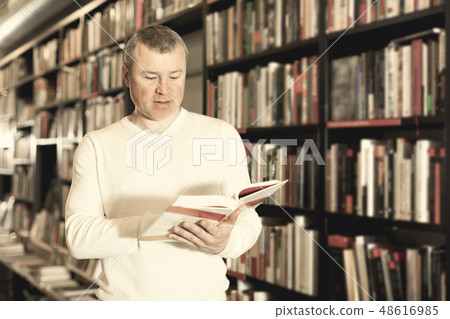 Male reading books in bookshop Male reading books in bookshop 48616985