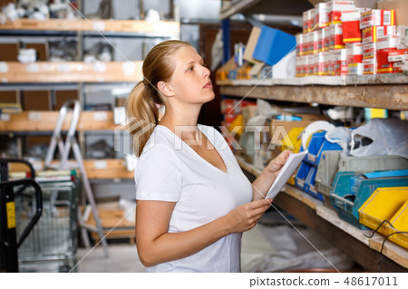 Portrait of young woman customer looking tools with note list in build store 48617011