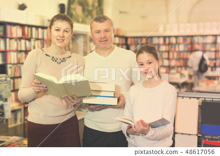 Adult family with daughter holding pile of books Adult family with daughter holding pile of books 48617056