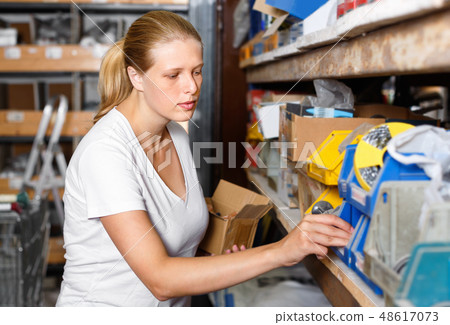 Young woman choosing construction materials at shelves in modern building shop 48617073