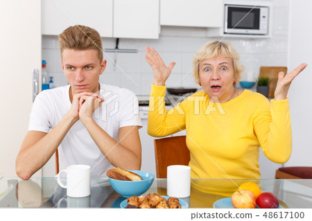 Woman scolding her upset adult son Woman scolding her upset adult son 48617100