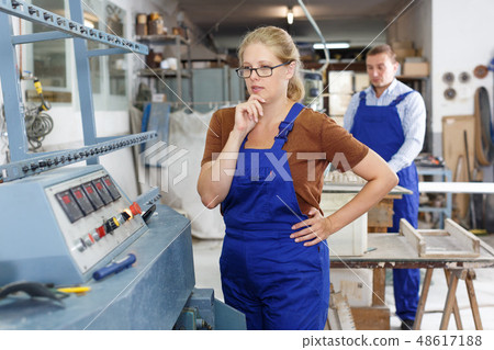 Female glazier working on glass bevelling machine 48617188