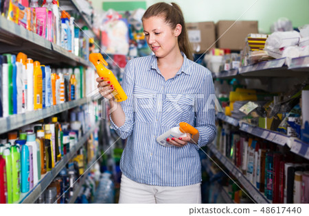 smiling woman choosing bottles of sun protection indoors smiling woman choosing bottles of sun protection indoors 48617440