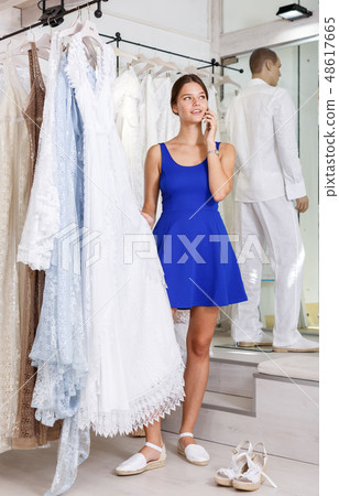 Girl choosing wedding dress and talking on phone Girl choosing wedding dress and talking on phone 48617665
