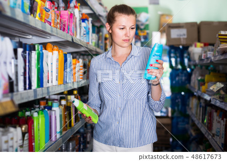 female holding shampoo and conditioner in the hand at the shop 48617673