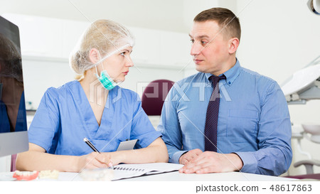 Female stomatologist listening to male patient 48617863